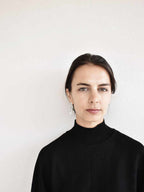 Woman wearing a pair of unique, organic-shaped silver stud earrings against a white background