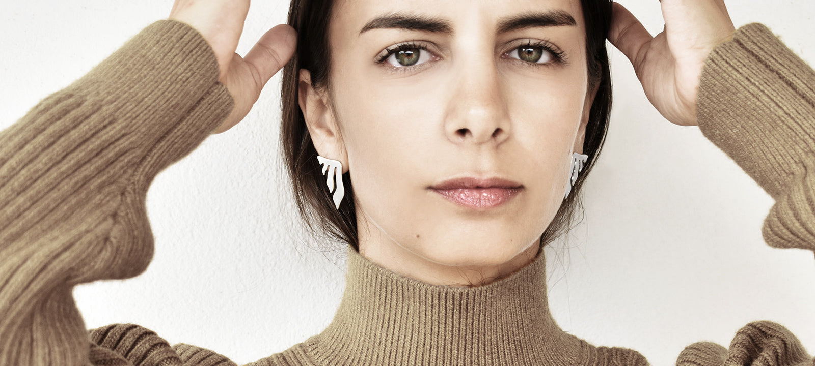 Woman wearing a pair of silver abstract earrings