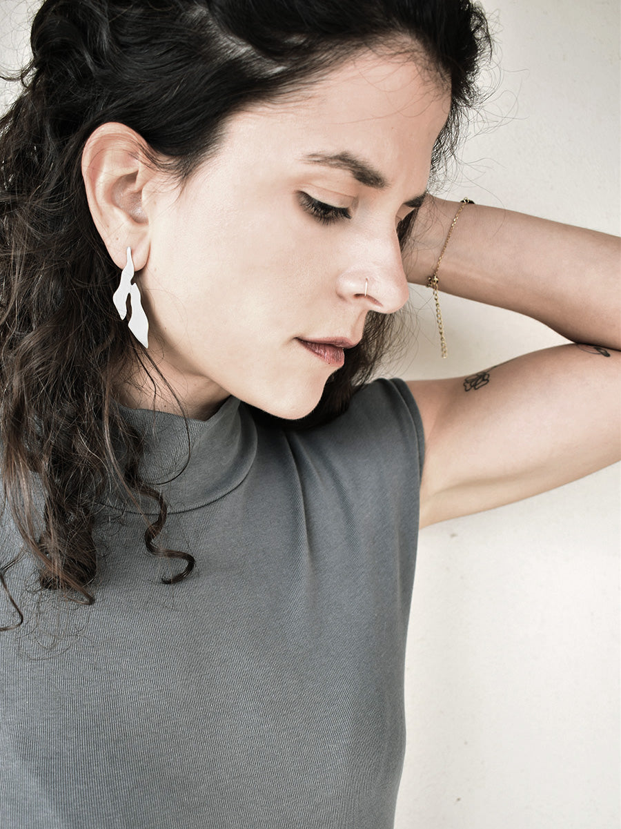 Woman wearing an abstract-shaped silver stud earring