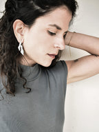 Woman wearing an abstract-shaped silver stud earring