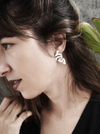 Woman wearing an organic-shaped silver stud earring with cutout details 