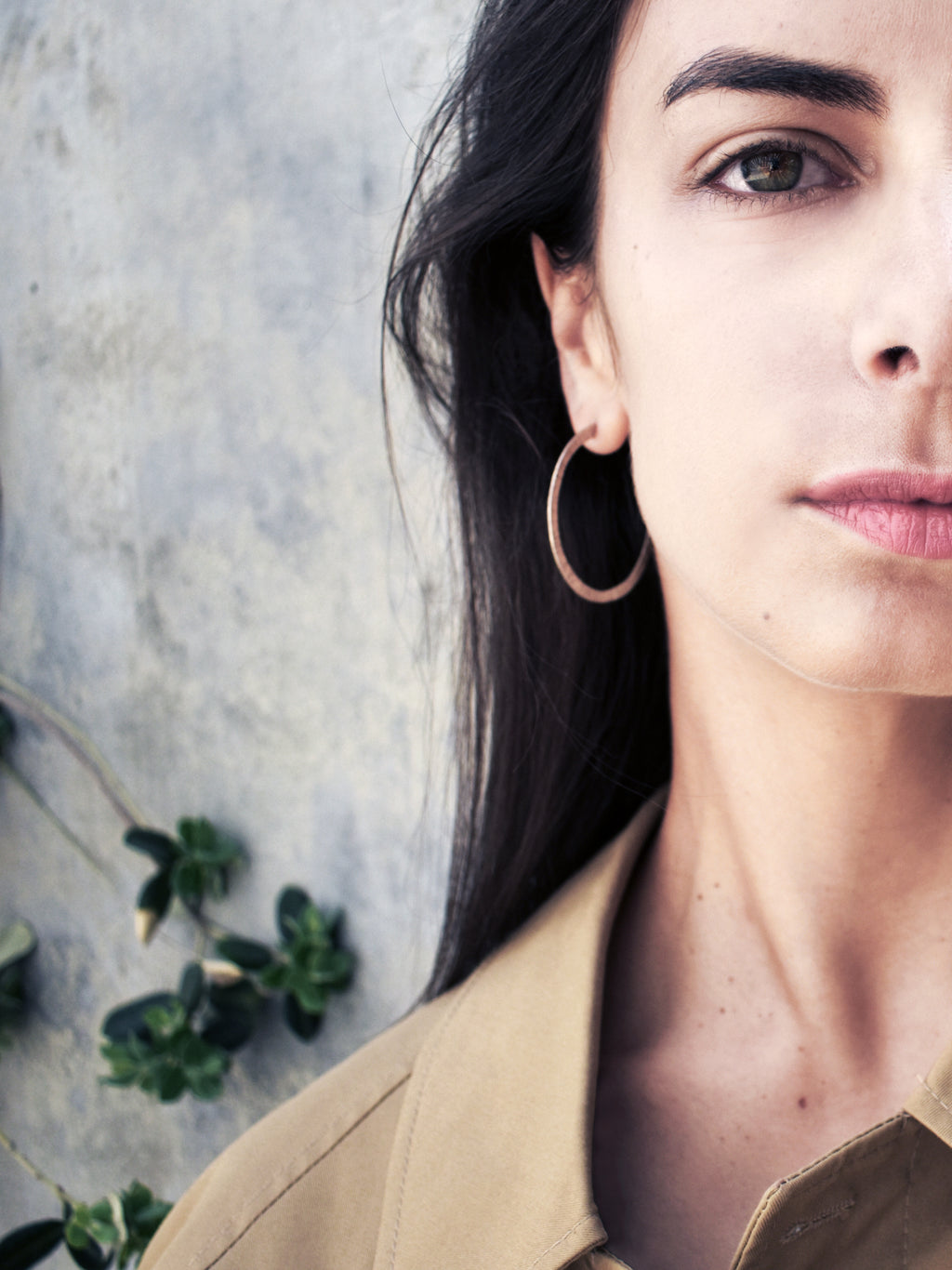 Close-up of a woman wearing a textured silver hoop earring