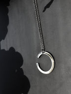 Silver crescent-shaped pendant with chain on a dark background