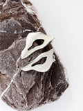 Pair of organic-shaped silver stud earrings with cutout centers on a textured stone