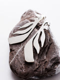 Pair of leaf-shaped silver stud earrings on a textured stone 