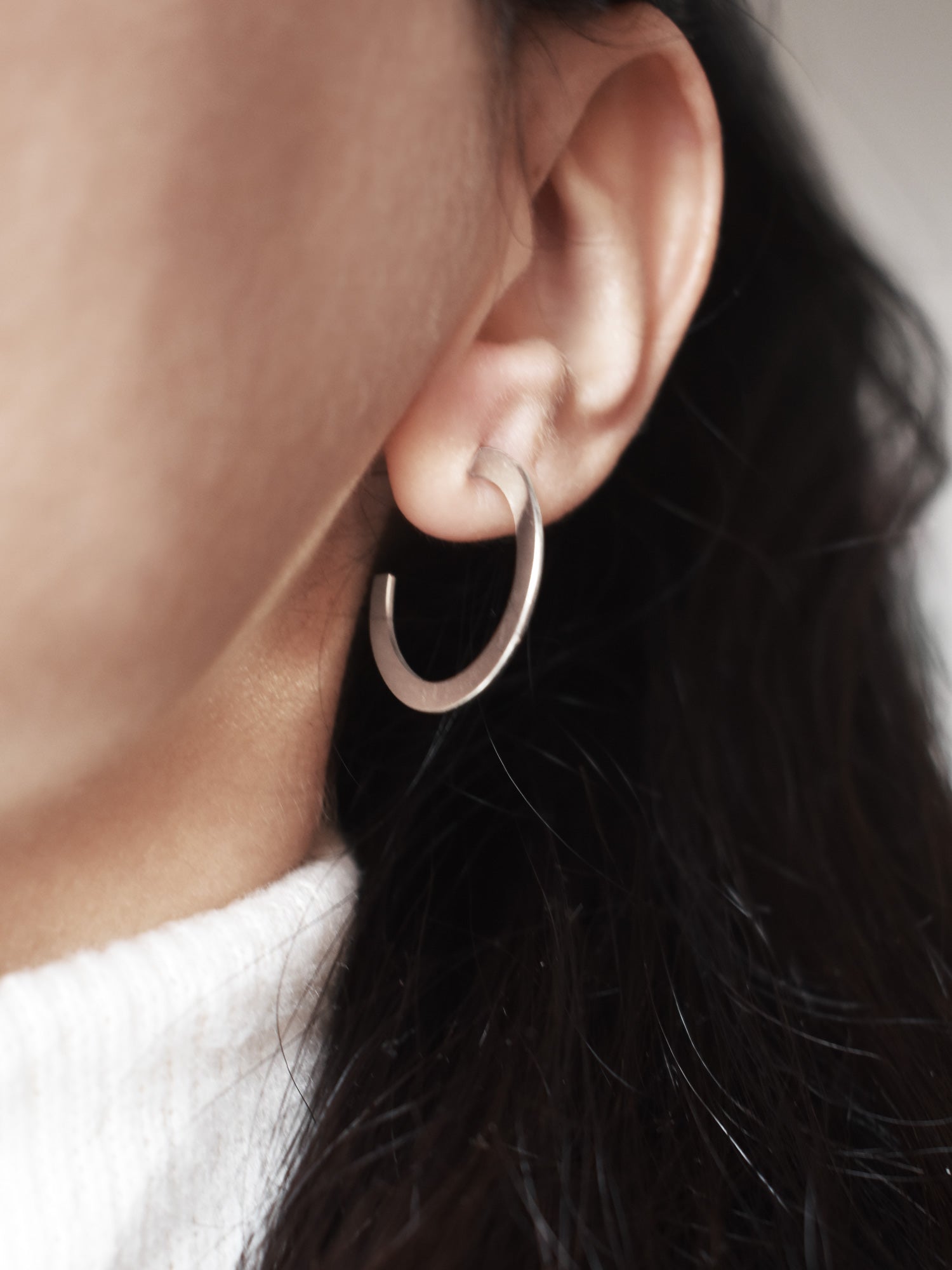 Close-up of a woman wearing a silver hoop earring 