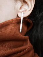 Close-up of a textured silver bar stud earring worn by a woman 