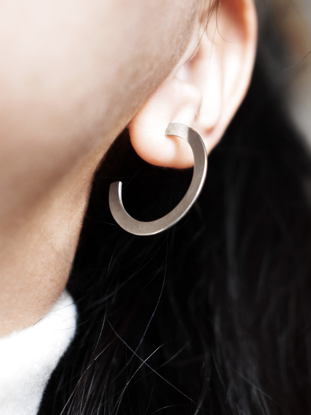 Close-up of a woman wearing a silver hoop earring 