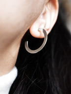 Close-up of a woman wearing a silver hoop earring 