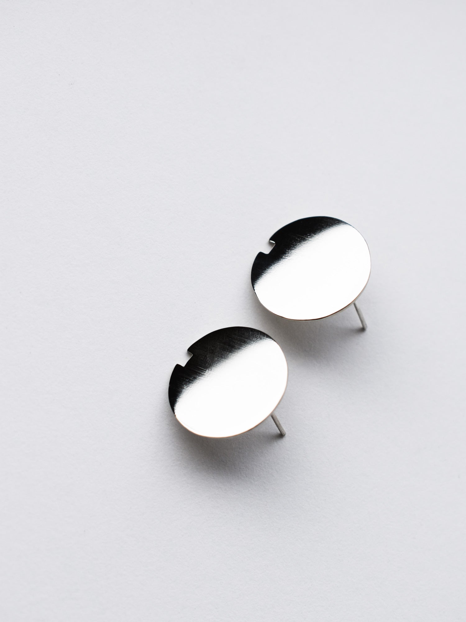 Pair of small circle silver stud earrings on a light gray background