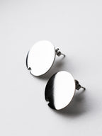 Close-up of pair of small circle silver stud earrings on a light gray background