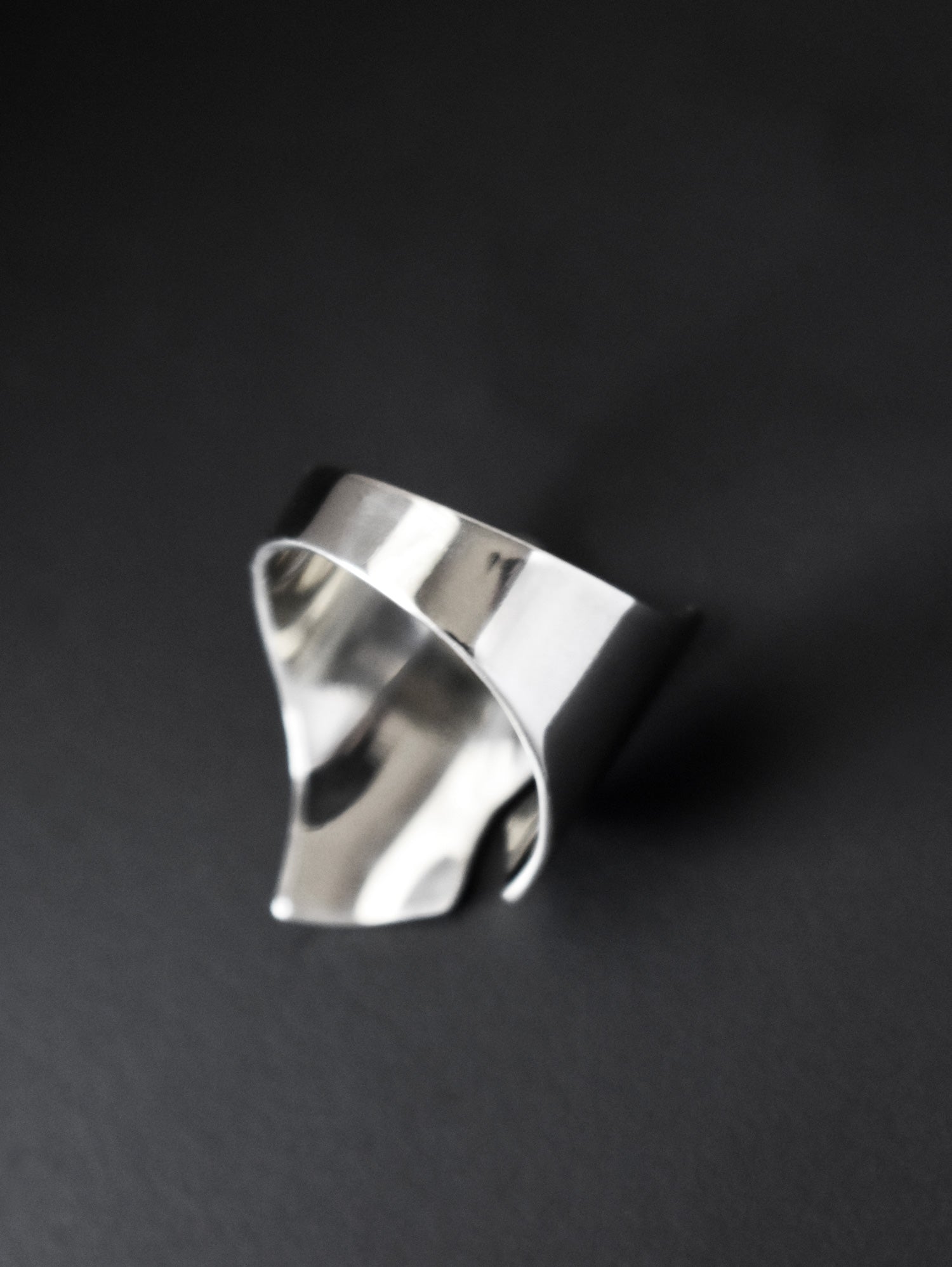 Adjustable sculptural silver ring on a black background