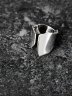 Adjustable sculptural silver ring on a dark textured surface