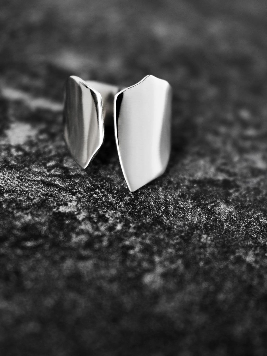 Adjustable sculptural silver ring on a dark textured surface