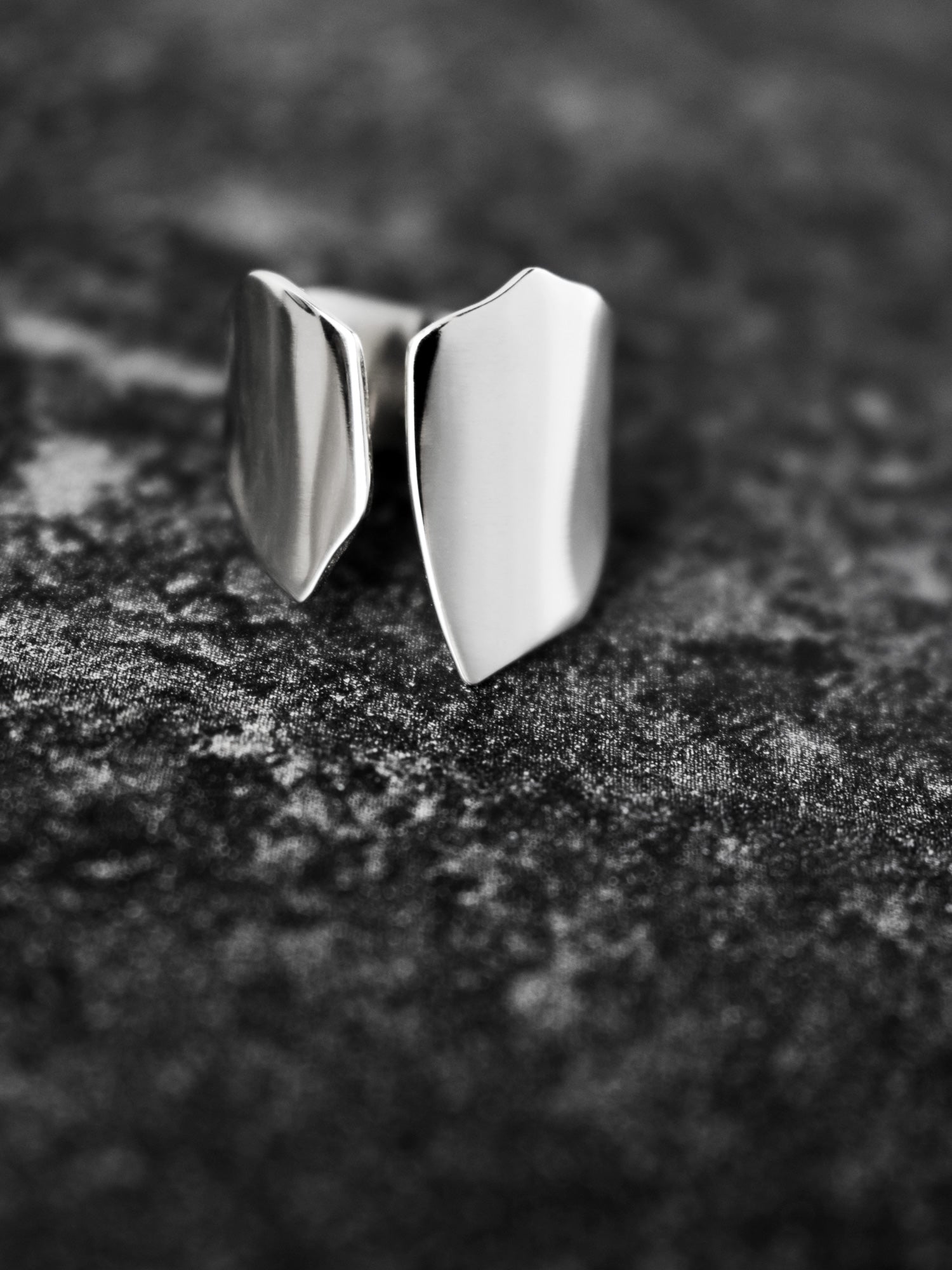 Adjustable sculptural silver ring on a dark textured surface