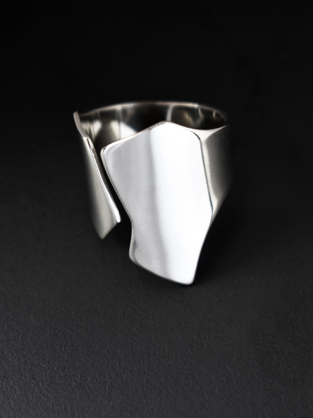 Adjustable sculptural silver ring on a black background