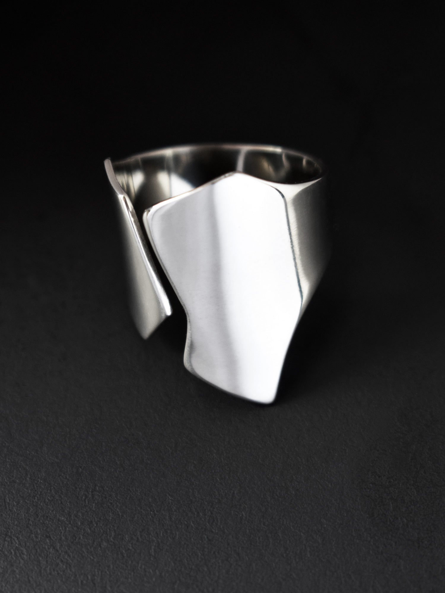 Adjustable sculptural silver ring on a black background