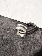 Adjustable double-band silver ring on a textured surface with a white background