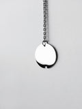 Small silver circle pendant with chain on a light gray background