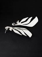 Pair of leaf-shaped silver stud earrings on a black background