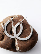 Pair of silver hoop earrings on a textured brown stone