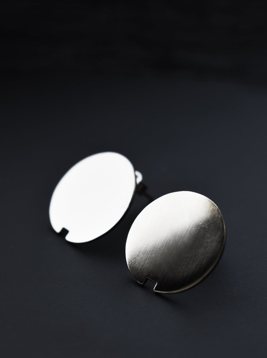 Pair of small circle silver stud earrings on a black background