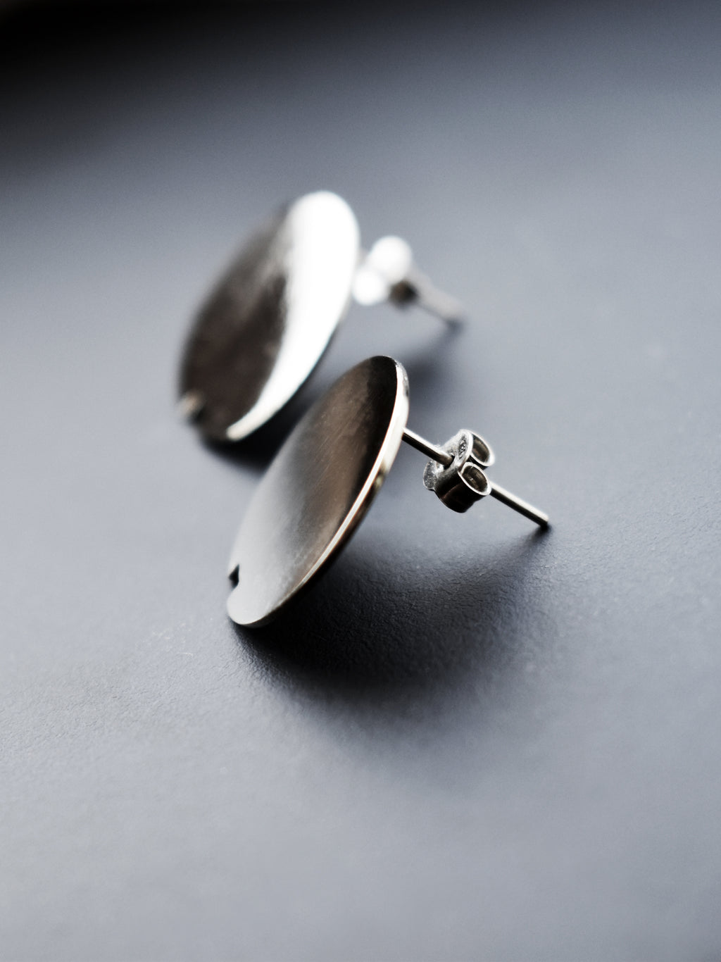 Pair of small circle silver stud earrings on a dark gray background