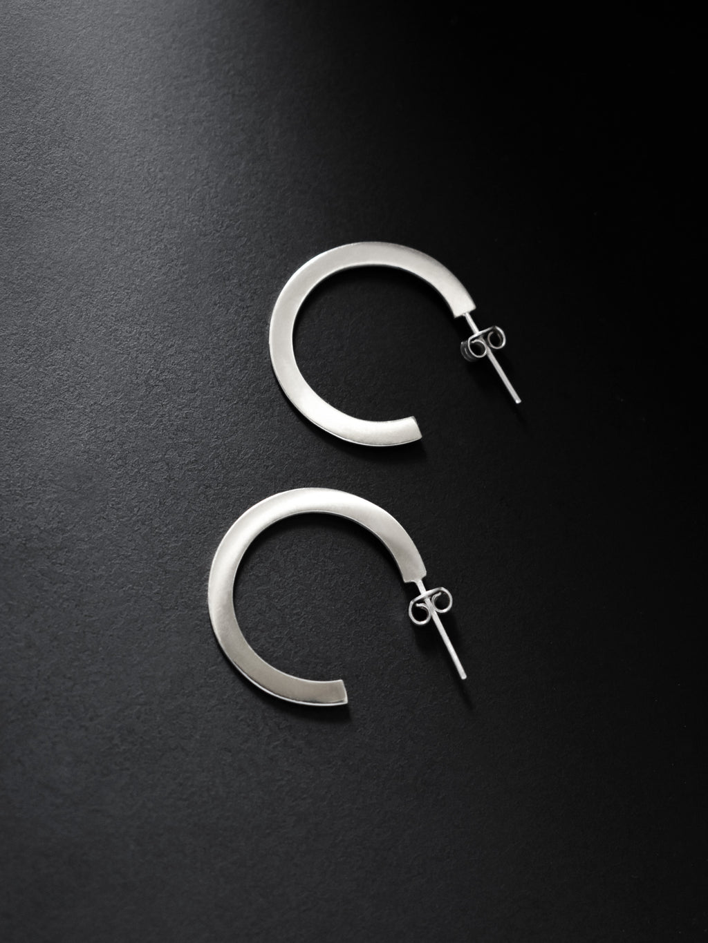 Pair of silver hoop earrings on a black background