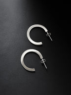 Pair of silver hoop earrings on a black background