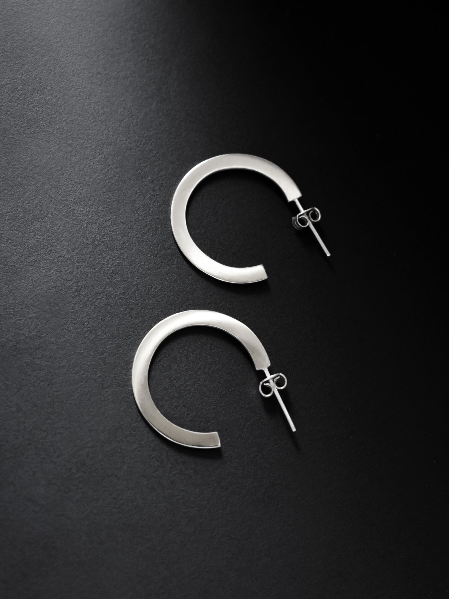 Pair of silver hoop earrings on a black background