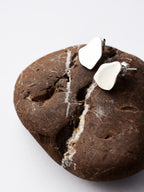 Pair of small organic-shaped silver stud earrings on a textured brown stone