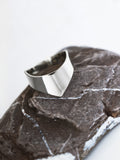 Adjustable silver ring with an angular band on a textured stone surface