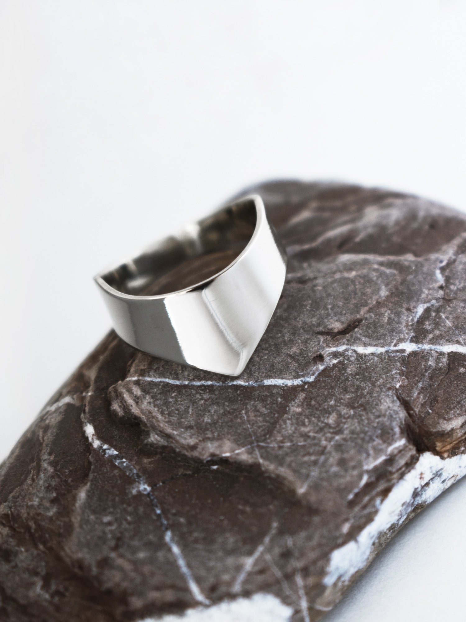 Adjustable silver ring with an angular band on a textured stone surface