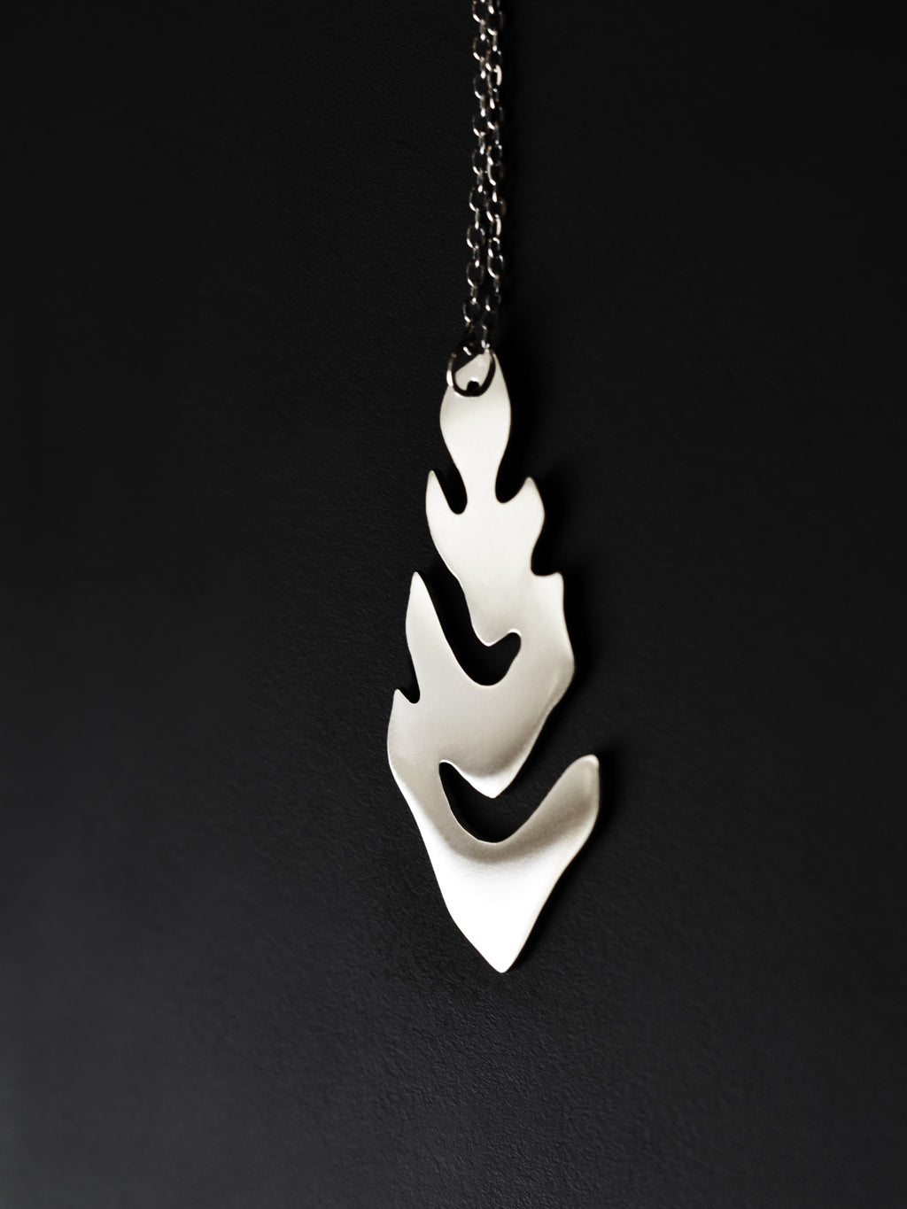 Silver leaf-shaped pendant with chain on a black background