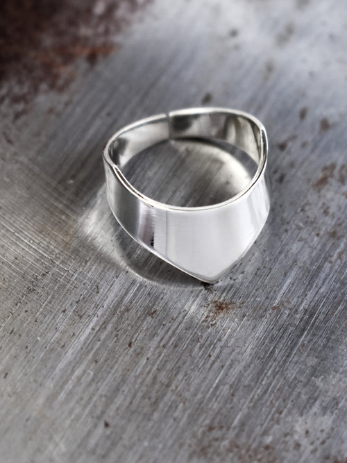 Adjustable silver ring with an angular band on a textured metal surface