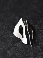 Pair of organic-shaped silver stud earrings with cutout centers on a black textured background