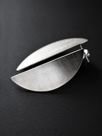 Pair of brushed silver semicircle stud earrings on a black background
