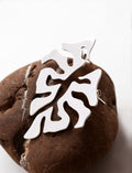 Pair of organic-shaped silver stud earrings with cutout details on a textured brown stone
