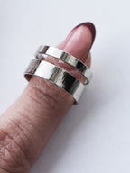 Adjustable double-band silver ring on a finger against a white background