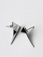 Pair of small curved triangular silver stud earrings on a light gray background
