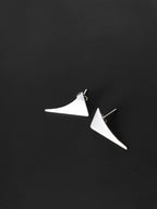 Pair of small curved triangular silver stud earrings on a black textured background