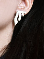 Close-up of a woman wearing an organic-shaped silver stud earring with flowing cutouts