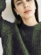 Woman wearing a pair of small organic-shaped silver stud earrings in a dark sweater