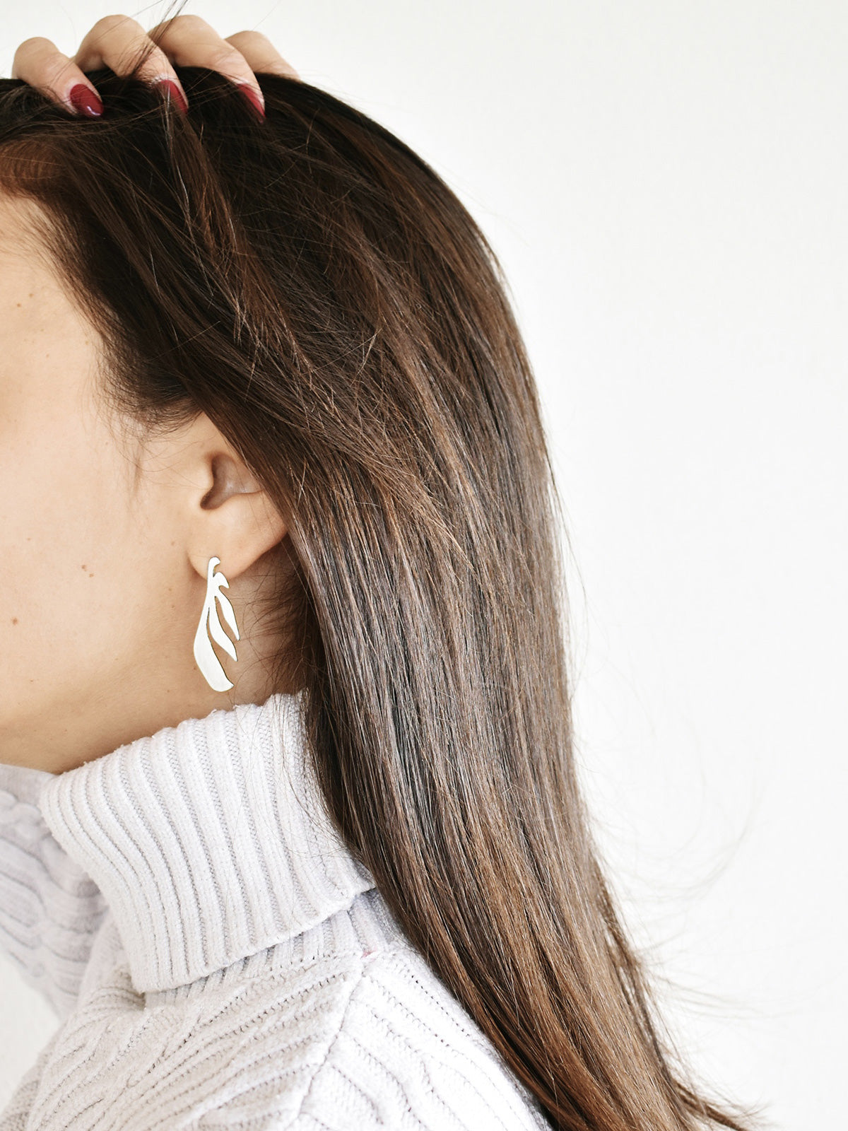 Close-up of a woman wearing a leaf-shaped silver stud earring