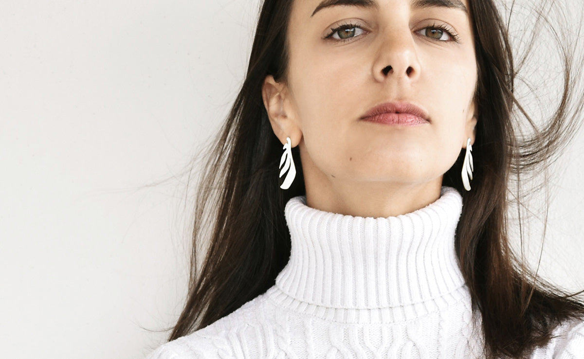 Woman wearing a pair of leaf shaped silver earrings